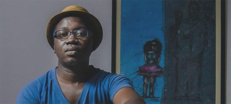   Gadi Ramadhani poses for a photograph next to one of his works themed Giants and the Girls.   PHOTO | ESTHER MNGODO